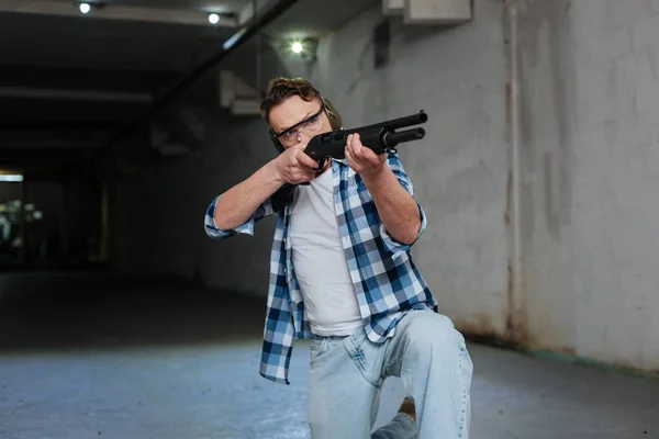 Confident skilled shooter sitting on one knee — Stock Photo, Image