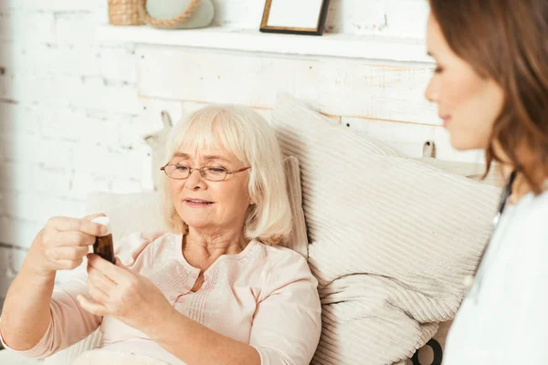 Assistente sociale utile che offre pillole al pensionato a casa — Foto Stock