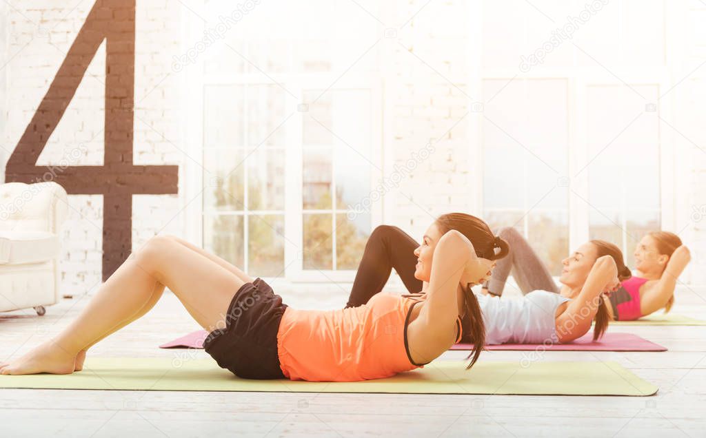 Youthful women doing abdominal crunches at gym