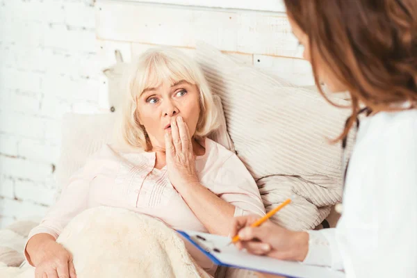 Mulher aposentada espantada conversando com terapeuta no hospital — Fotografia de Stock