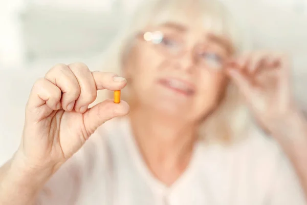 Neugierige Rentnerin betrachtet Pille zu Hause — Stockfoto