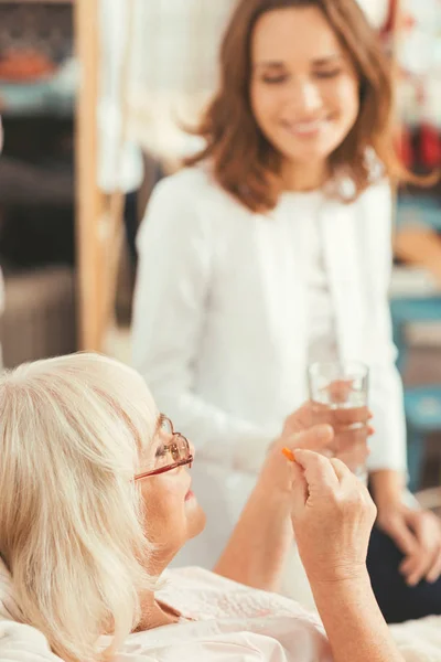 Careful old woman taking medicament at home — Stock Photo, Image