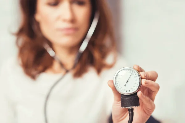 Mulher jovem grave demonstrando índice de pressão arterial em casa — Fotografia de Stock