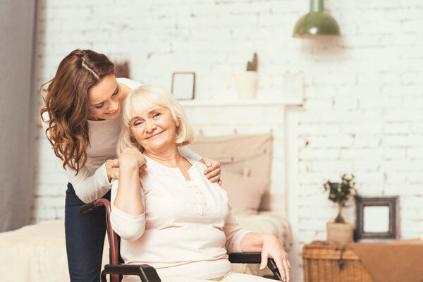 Young woman taking care of ill mother on wheelchair