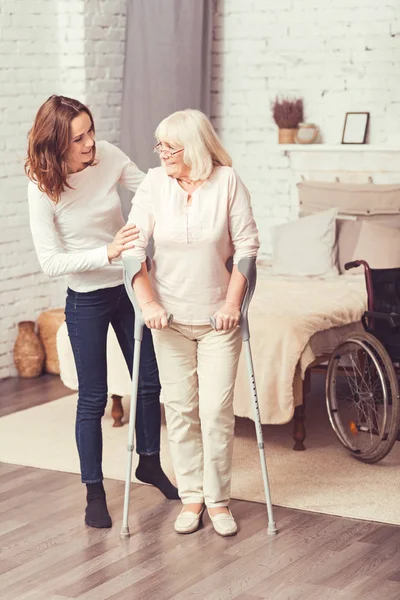 Hilfsbereite junge Frau hilft behinderter Mutter zu Hause — Stockfoto