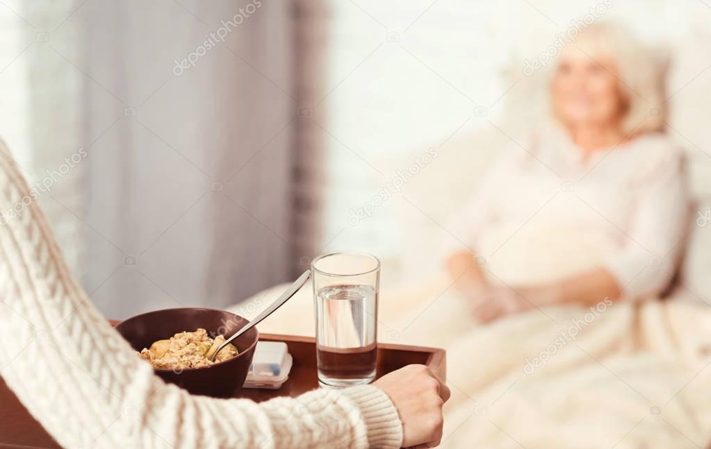 Peaceful nurse carrying tray to the patient in the hospital ward