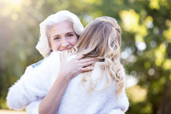 Ελκυστική συνταξιούχος αγκαλιάζει κόρη σε εξωτερικούς χώρους — Φωτογραφία Αρχείου