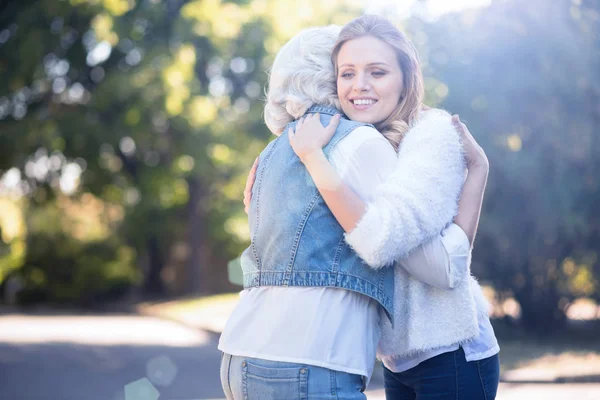 woman hugging old mother outdoors