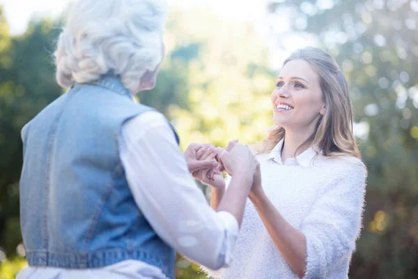Женщина, держащаяся за руки с бабушкой в парке — стоковое фото