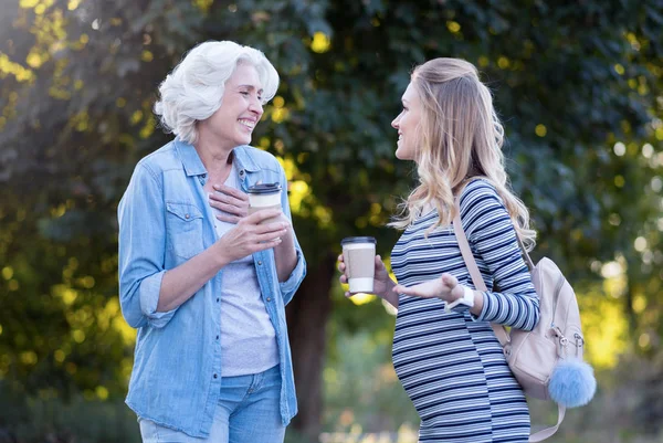 Joyful pregnant woman enjoying conversation with aged mother outdoors — Stock Photo, Image