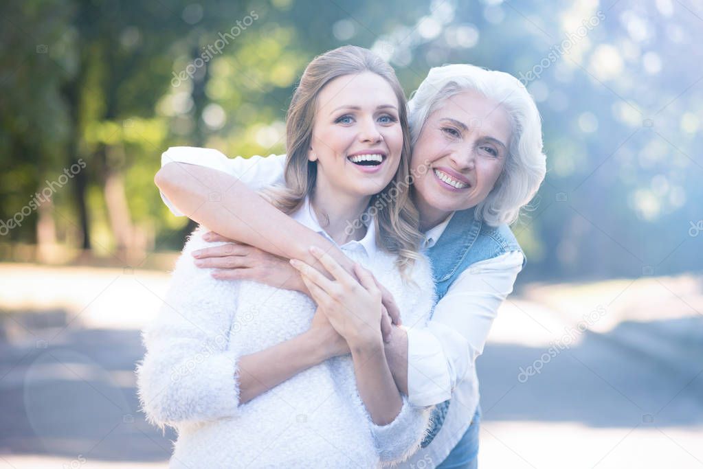 elderly mother hugging woman in park