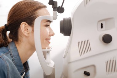 Cheerful female patient having her vision checked clipart