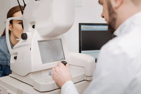 Professional male doctor using eye testing equipment — Stock Photo, Image