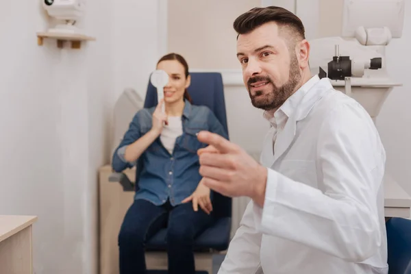 Entzückter angenehmer Arzt zeigt auf die Augenkarte — Stockfoto