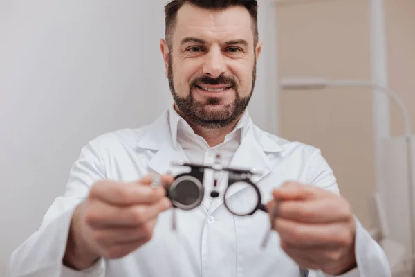 Dokter mata ramah yang ceria memegang kacamata tes mata. — Stok Foto