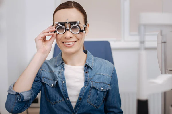 Delighted beautiful woman fixing the eye test glasses — Stock Photo, Image