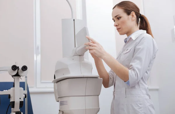 Serious female doctor choosing the settings — Stock Photo, Image