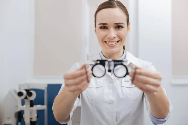 Lebensfrohe freundliche Augenoptikerin, die Ihnen eine Brille anbietet — Stockfoto