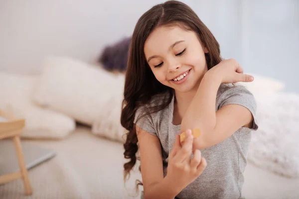 Leende flicka att ta hand om hennes sår på armbågen — Stockfoto