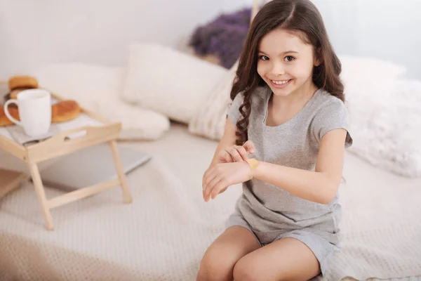 Ragazzo allegro mettere bendaggio aiuto sul braccio a casa — Foto Stock