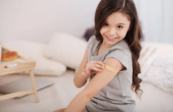 Chica feliz aplicando parche médico en el brazo en casa — Foto de Stock
