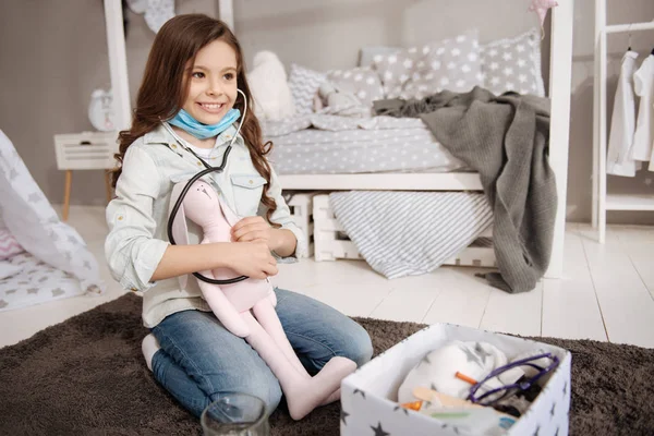 Chica sonriente curando conejito de peluche en el dormitorio —  Fotos de Stock