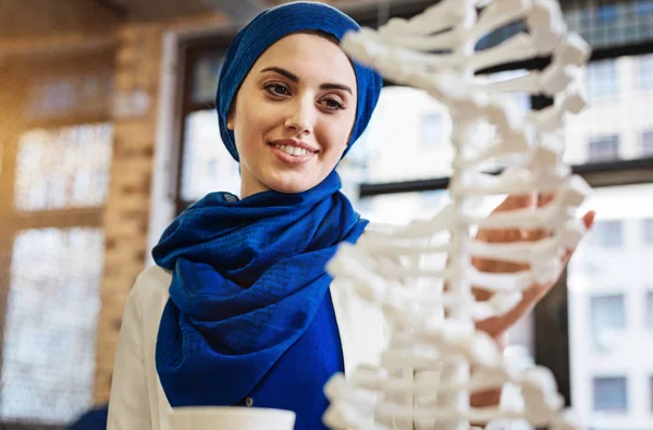 Позитивная привлекательная мусульманка, изучающая модель ДНК — стоковое фото