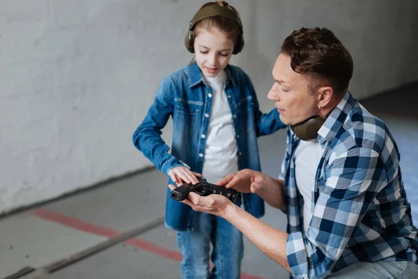 Ganska nyfiken flicka vidrör en pistol — Stockfoto