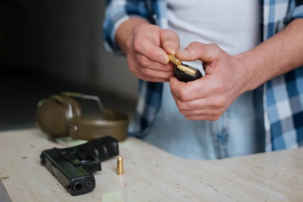 Nice pleasant man putting a bullet into the cartridge clip — Stock Photo, Image