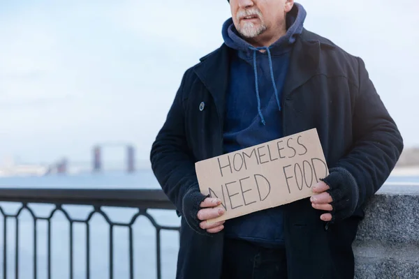 Бездомный пенсионер стоял с бумагой в руках — стоковое фото