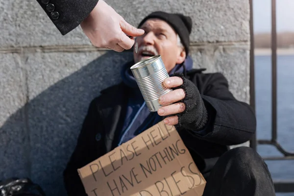 Feliz hombre de pelo gris manteniendo lata para la donación —  Fotos de Stock