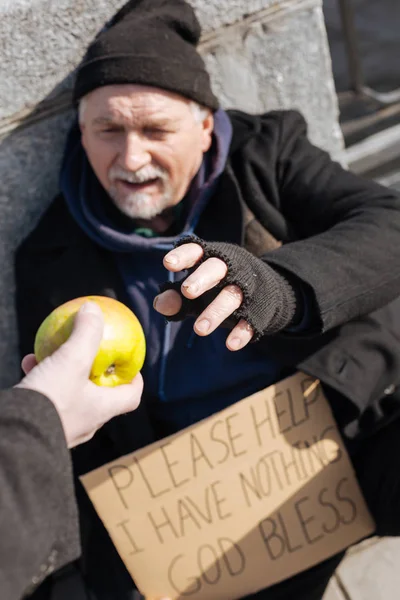 Needy elderly man taking apple — Stock Photo, Image