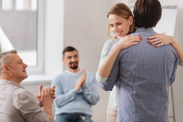 Mujer joven positiva cogida de la mano sobre hombros masculinos — Foto de Stock