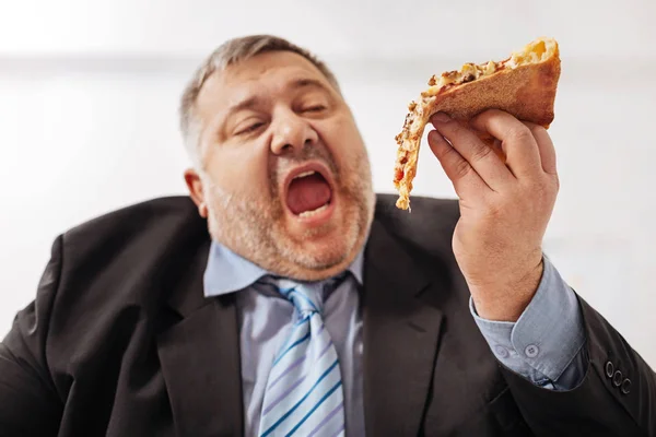 Fanatical obese man biting a slice of pizza — Stock Photo, Image