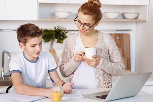 Pleasant little boy doing home assignment with his mother — Stock Photo, Image