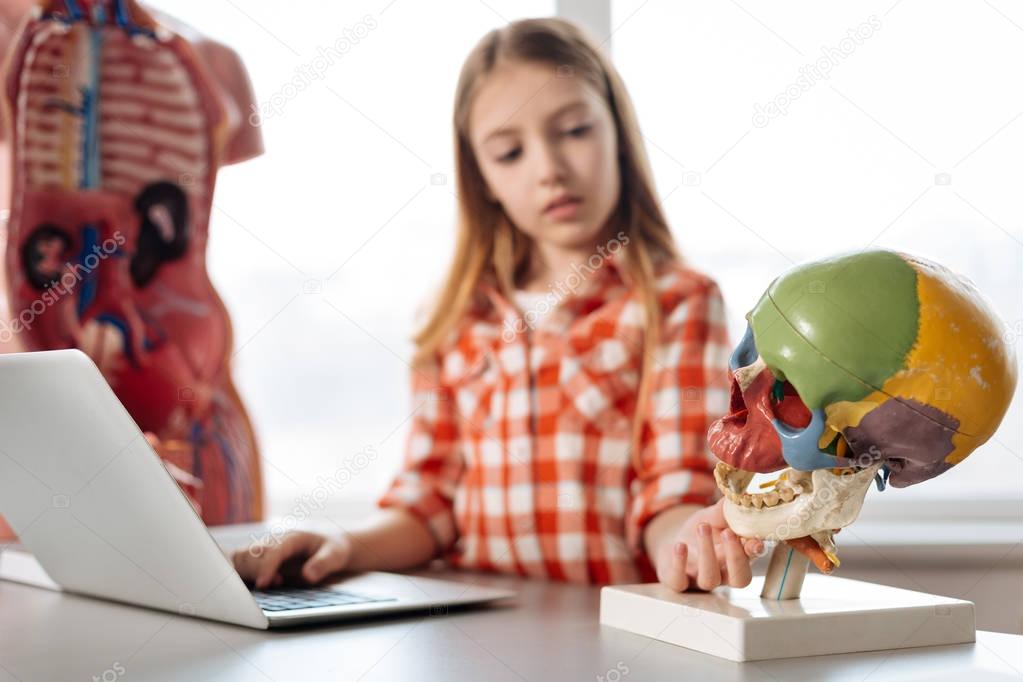 girl examining skull model in class 