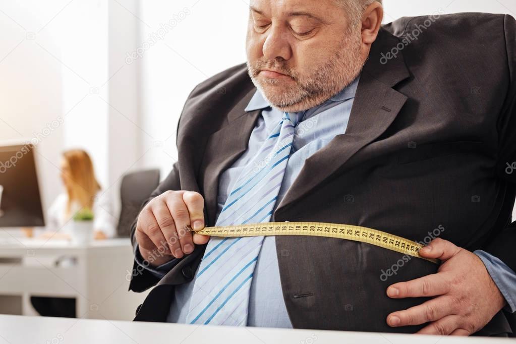Concerned overweight office worker taking measurements