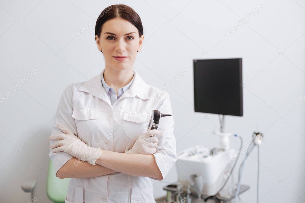 Serious medical worker holding otoscope in hand