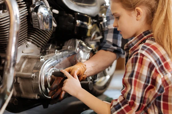 Curiosa chica encantadora tocando detalles de una motocicleta — Foto de Stock