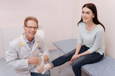Friendly professional rheumatologist happy assisting his patient clipart