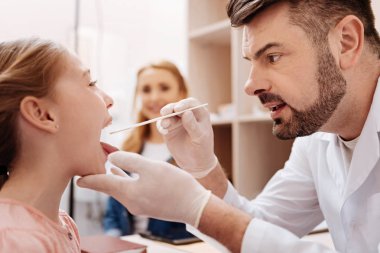 Kendine güvenen Doktor hastasına ağzına bakıyor