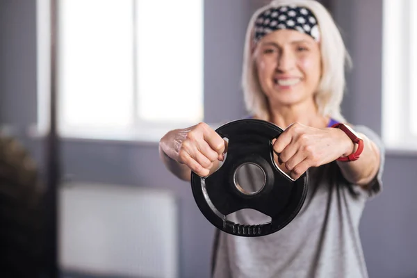 Gewicht schijf wordt in handen van een leuke gezellige vrouw — Stockfoto