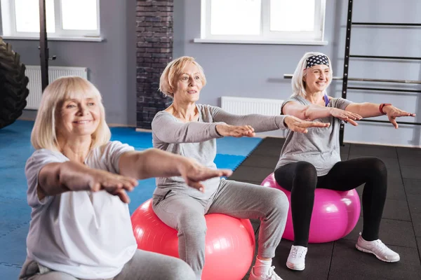 Mulheres ativas alegres se exercitando em bolas de fitness — Fotografia de Stock
