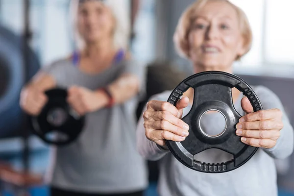 Gewichtsscheibe in den Händen einer aktiven sportlichen Frau — Stockfoto