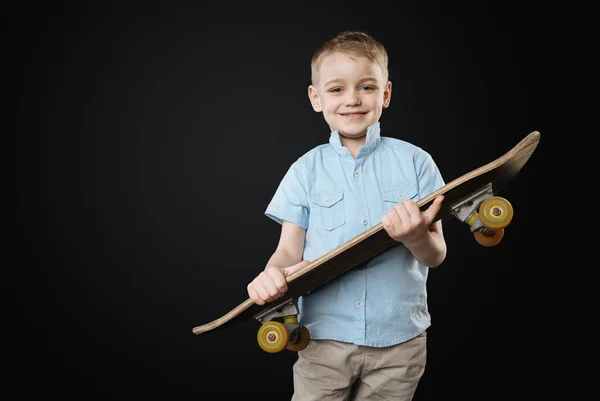 Very young sportsmen holding skateboard in both hands — Stock Photo, Image