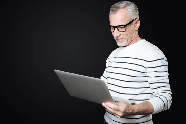 Позитивный пожилой человек смотрит на свой ноутбук — стоковое фото