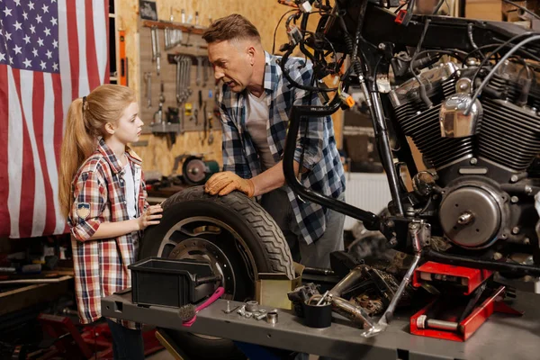 Attentif fille intéressée aider son père changer un pneu — Photo