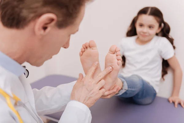 Thorough determined specialist comparing the state of the feet — Stock Photo, Image