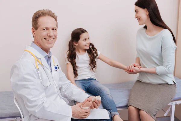 Médico local brilhante recebendo visita de uma família — Fotografia de Stock