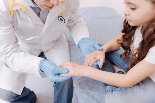 Забавная маленькая девочка показывает врачу свои раны — стоковое фото